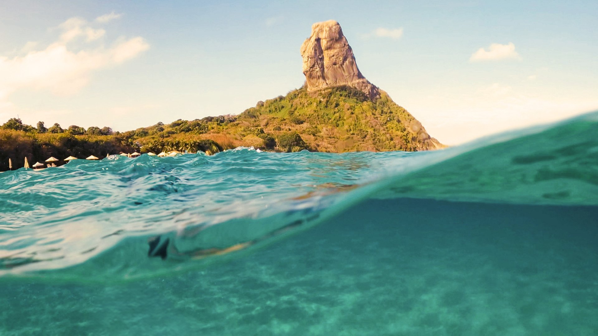 Mar transparente com o Morro do Pico ao fundo